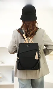 Rear view of model wearing black nylon anti-theft backpack with brown leather accents