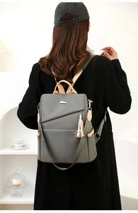 Detail of dark grey nylon backpack with brown leather handle and stylish fringe tassel