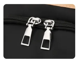 Dettaglio di doppie cerniere in metallo argento su zaino in nylon nero e finiture in pelle