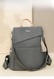 Close-up of gray nylon backpack featuring leather handles and stylish fringe tassel detail