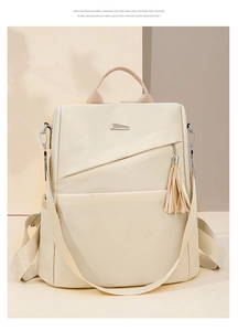 Detail of beige nylon backpack featuring geometric metal logo and stylish tassel pendant