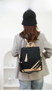 Rear view of a model wearing the black nylon backpack with beige trim and stylish long tassels