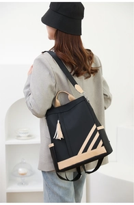 Side view of two-tone PU leather backpack showing beige straps and side pockets on model