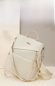 Detail of beige nylon backpack showing versatile straps and fringe tassel decoration