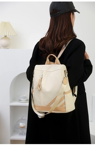 Detail of contrast PU leather backpack with tassel zipper and wide fabric strap on model