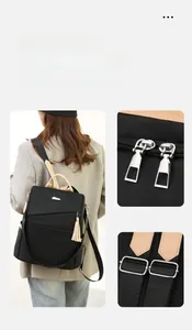 Detail of nylon backpack featuring silver dual zippers and beige leather tassel accent