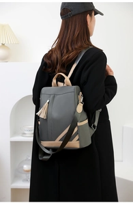 Detail of grey and beige PU leather backpack with decorative tassel and adjustable strap