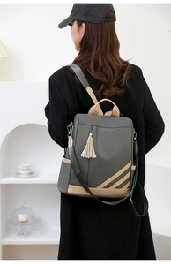 Detail of color-block PU leather backpack with tassel showing side pockets and straps