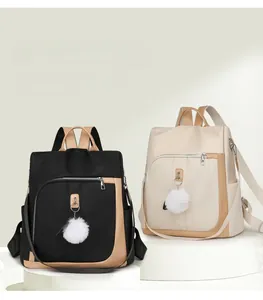 Dettaglio di zaini antifurto bicolore nero e beige con ciondolo a pompon bianco