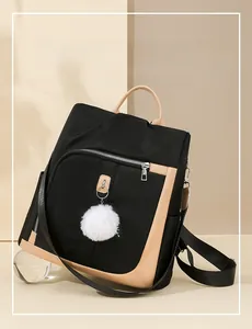 Dettaglio dello zaino in nylon nero impermeabile con finiture in pelle kaki e ciondolo a pompon