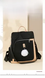 Dettaglio dello zaino in nylon con finiture cammello e ciondolo a pompon in peluche bianco