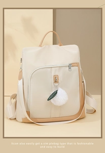 Dettaglio zaino in nylon beige con tasca anteriore e ciondolo a pallina di pelo