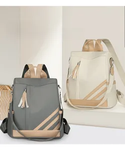 Detail of contrast color PU leather backpacks with stylish tassels and multi-pocket storage