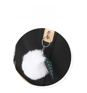 Dettaglio di uno zaino nero alla moda con un pompon bianco e decorazione a foglia verde