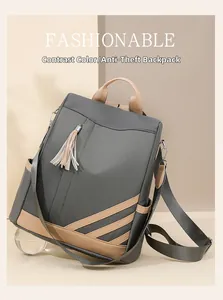 Detail of color contrast anti-theft backpack with stylish tassel charm and hand strap
