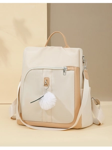 Dettaglio zaino beige con ciondolo a pompon bianco e rifiniture in pelle di alta qualità