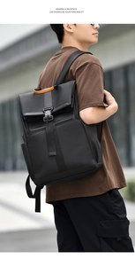Detail of ergonomic padded shoulder straps on a black travel backpack with orange handle