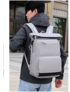 Outdoor shot of a light grey waterproof backpack with roll-top closure and large front pocket