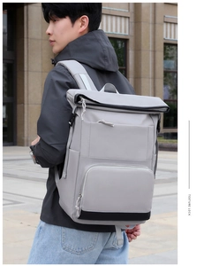 Side view of light grey insulated backpack with roll-top and buckle on male model