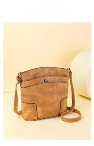 Detail of vintage caramel brown multi-pocket crossbody bag with metallic rivets