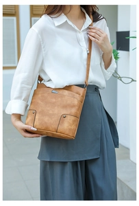 Close-up of vintage brown textured PU leather handbag with metal rivets and strap