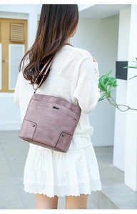 Close-up of vintage Morandi purple leather crossbody bag worn with a white lace dress