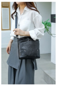 Detail of vintage black crossbody bag with layered texture and metal decorative buckle