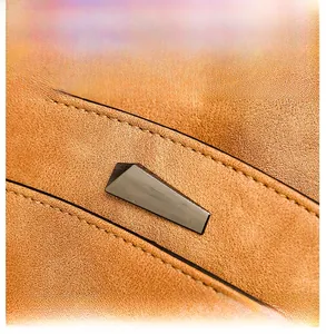 Detail of brown faux leather bag showing geometric metal buckle and precise stitching