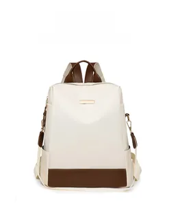 Détail du sac à dos beige en tissu Oxford avec garniture en cuir brun et zips dorés