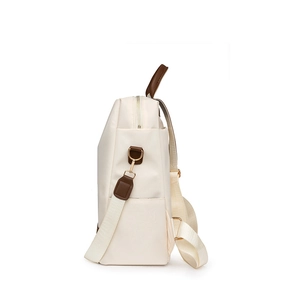 Détail d'un sac à dos oxford crème avec sangle en cuir marron et fermeture éclair dorée