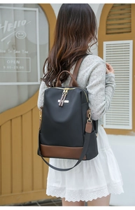 Détail du sac à dos en nylon noir étanche avec finitions en cuir brun et métal doré