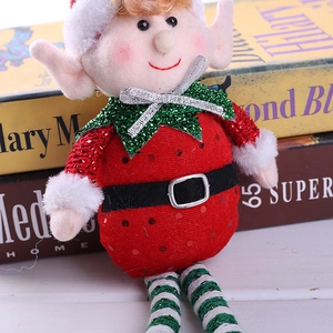 Plush Christmas elf doll with strawberry motifs and green striped legs on a book