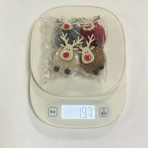 Detailed view of four colorful reindeer plush ball ornaments on a digital scale weighing 19.7g