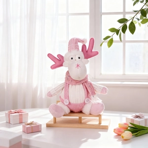 Detailed plush pink reindeer figurine sitting on a bench with winter knit accessories