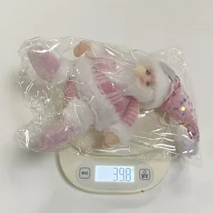 Macro shot of pink sequined Santa Claus plush ornament being weighed on electronic scale
