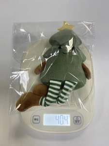 Green plush Christmas tree toy with striped legs on a scale weighing 40.4 grams