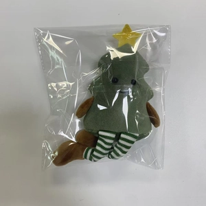 Detail showing a plush Christmas tree doll with long striped legs in protective packaging