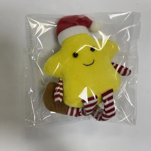 Detail of yellow star plush toy with a red Christmas hat in clear plastic packaging