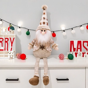 Detail of Christmas sitting gnome doll with snowflake sweater and long legs on white shelf
