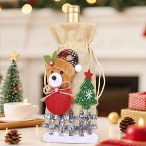 Close-up of burlap Christmas wine gift bag with plush bear and green sequin tree decor