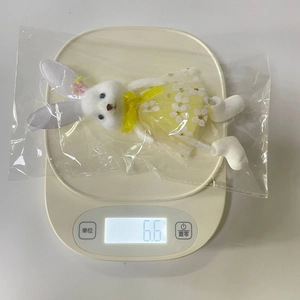 Detail view of cute Easter bunny plush doll in floral dress being weighed at 6.6g