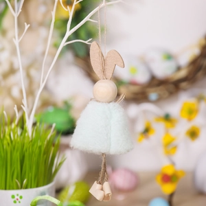 Detail von Osterhasen-Deko mit Filzohren und Plüschkleid an einem Baumzweig