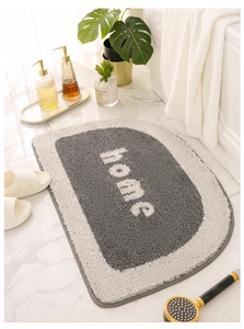 Detail of semicircular gray absorbent bath mat with home lettering on marble floor