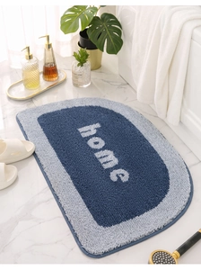 Detail of tufted semi-circular bath mat with Home text on white marble floor