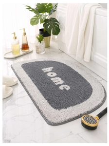 Detail of a semi-circular bathroom mat with plush gray and white fiber and home text