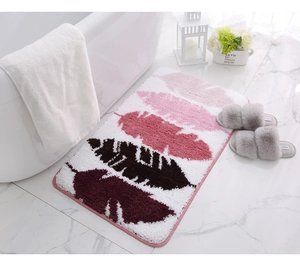 Primer plano de una alfombra de baño suave con patrones de plumas sobre mármol