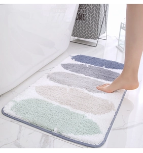 Primer plano de alfombra de baño nórdica con diseño de plumas junto a una bañera blanca