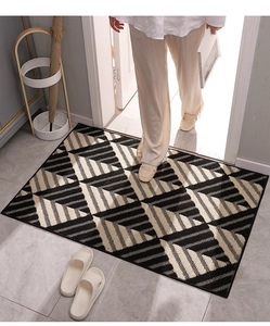 Top-down view of modern geometric black and beige entrance mat in home hallway setting