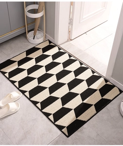 Detail view of woven doormat featuring 3D honeycomb pattern on a grey tile floor