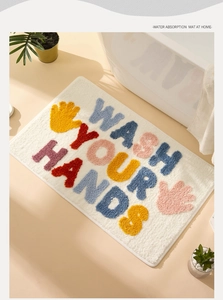 Close-up of thick tufted bath mat with colorful Wash Your Hands text and palm prints